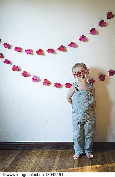 Süßer Junge trägt eine herzförmige Sonnenbrille  während er an der Wand steht