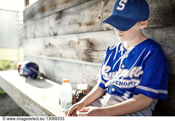 Sad boy relaxing while sitting in dugout