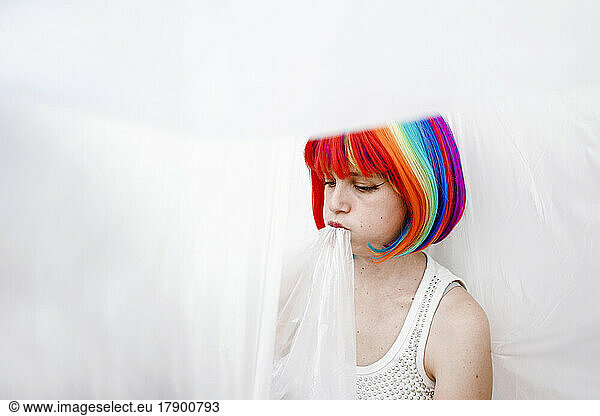 Sad woman in colorful dyed hair biting plastic