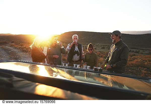 Safari-Gruppe trinkt Champagner bei Sonnenuntergang
