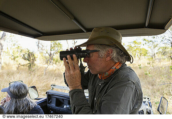 Safari guide using binoculars in a jeep with a family
