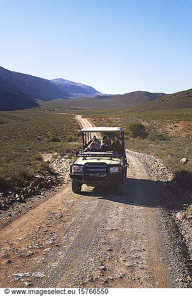 Safari off-road vehicle driving along sunny remote road South Africa