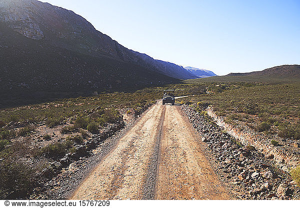 Safari off-road vehicle driving on sunny remote dirt road South Africa