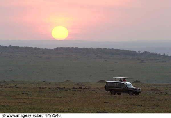 Safari Touristen in Wildbeobachtungsfahrzeug Sonnenaufgang über der Savanne Masai Mara Kenia Afrika