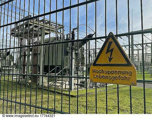 Safety fence with warning sign High voltage Danger to life  behind it transformer in substation for power supply  North Rhine-Westphalia  Germany  Europe