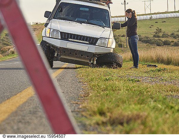 Safety triangle warning of a car accident on the side of the road with woman on the phone  South Africa