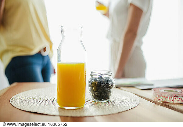 Saft und Obst auf dem Tisch mit Frauen  die zu Hause Saft trinken  im Hintergrund
