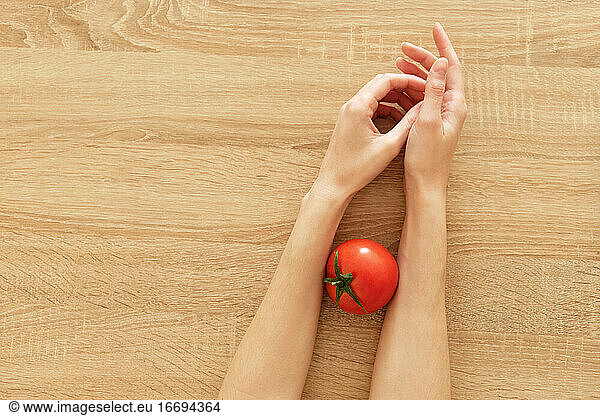 saftige Tomate in den Händen auf hölzernem Hintergrund tomato-'mäto t?'mato ??????