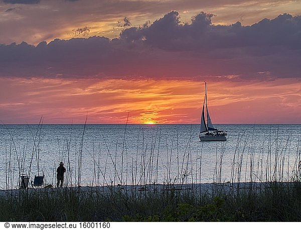 Sailboat in the Gulf of Mexico at sunset with an orange sky off Nokomis Beach ion the Gulf coast of Florida.
