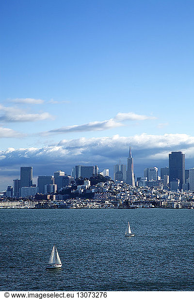 Sailboats on San Francisco Bay by city against blue sky