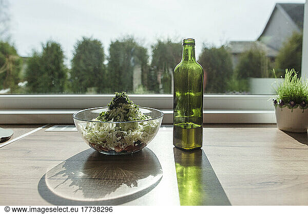 Salad bowl and bottle of olive oil at the window