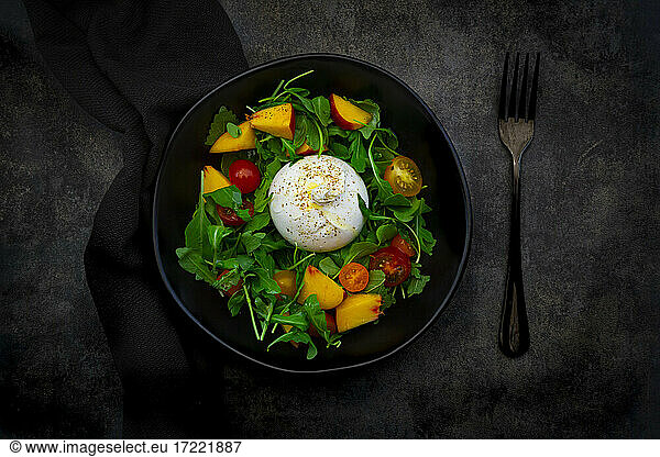 Salad made out of rocket  nectarine  tomatoes  lemon balm  basil and burrata cheese