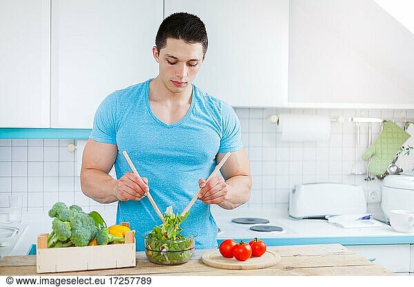Salat zubereiten essen junger Mann Mittagessen Küche gesunde Ernährung Textfreiraum Copyspace in Deutschland