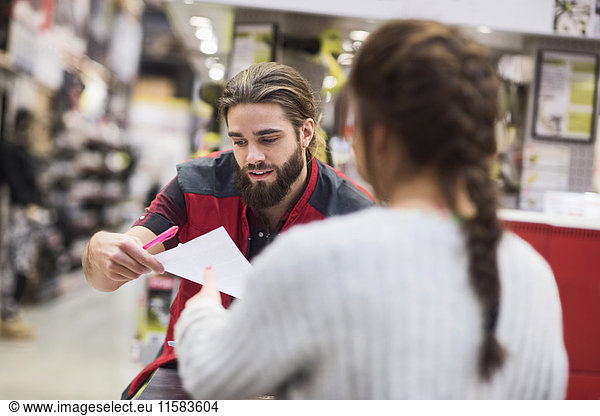 Salesman giving document to female customer in hardware store