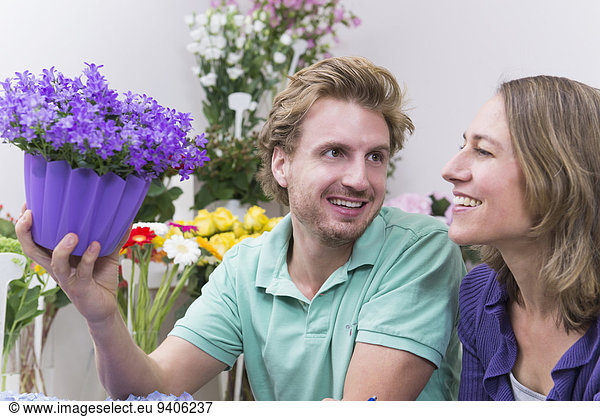 Salesman with customer holding potted plant  smiling