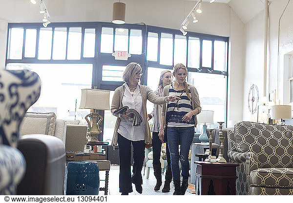 Saleswoman showing furniture to female customers in store