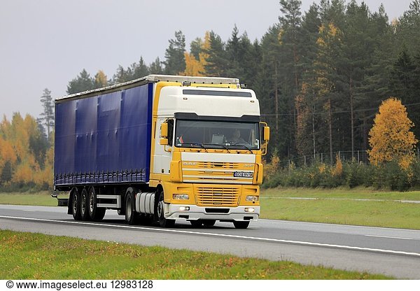 Salo  Finland - October 12  2018: Yellow and white DAF XF semi truck at speed on freeway in South of Finland on a foggy day of autumn.