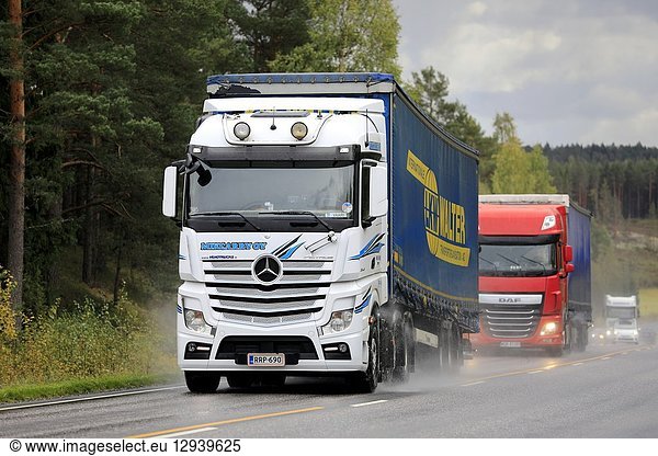 Salo  Finland - September 28  2018: White Mercedes-Benz and red DAF freight semi truck traffic on wet road on rainy autumn day in South of Finland.