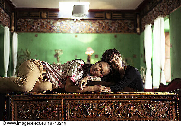 Same sex lesbian couple sit in colourful Colonial Spanish apartment