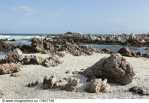 Sand- und Kieselstrand mit zerklüfteten Felsen an der Atlantikküste.