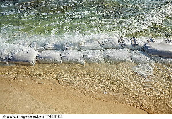 Sandbags in rows at the water's edge to prevent erosion of the beach