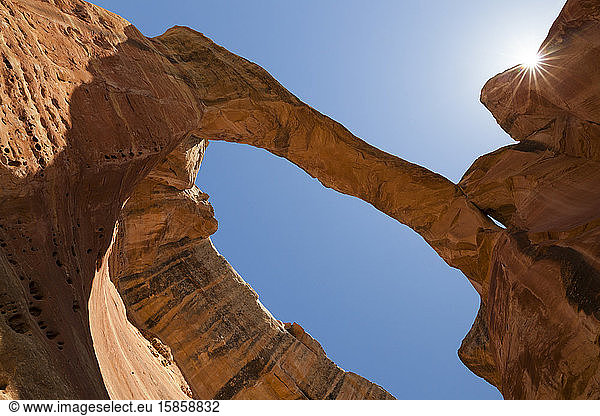 Sandstone rock arch with sunburst against blue sky in Colorado