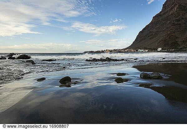 Sandy beach beach with stones  reflection from the sky  behind village La Playa  Valle Gran Rey  La Gomera  Canary Islands  Spain  Europe