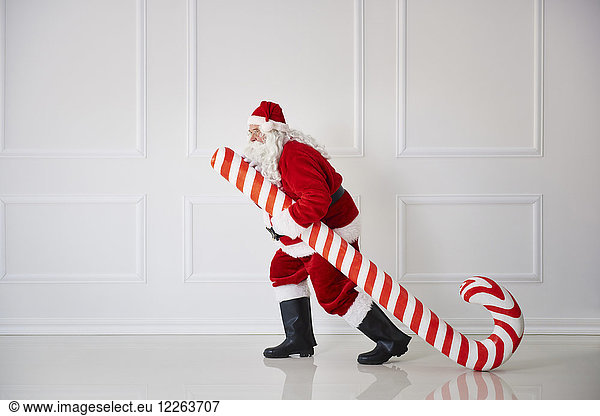 Santa Claus carrying oversized candy cane