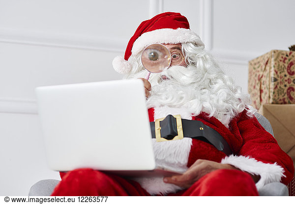 Santa claus using laptop with magnifier