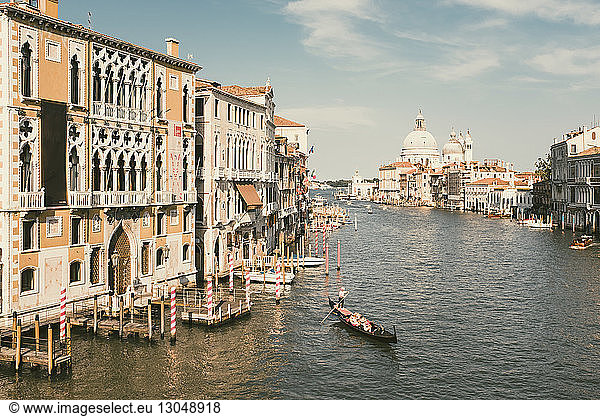 Santa Maria Della Salute by canal amidst buildings against sky