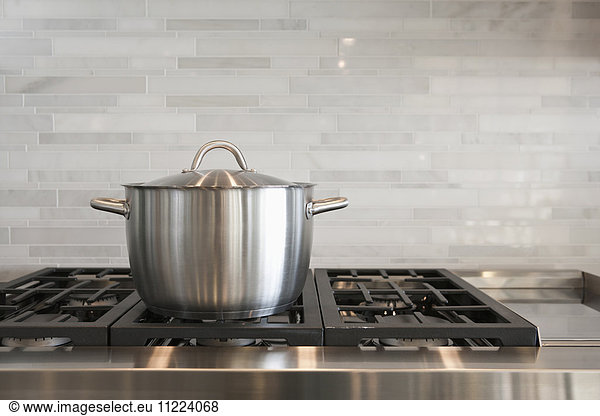 Sauce pan on burner with backsplash in kitchen