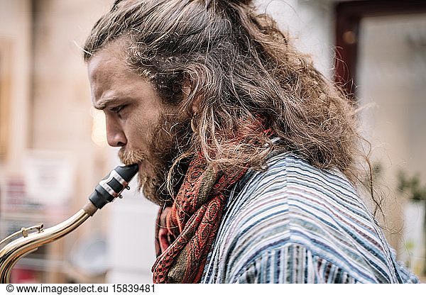 Saxophonist with long hair and beard playing in the street