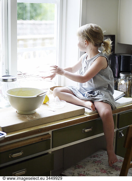 Scandinavia  Sweden  Girl preparing food in kitchen  looking out of window