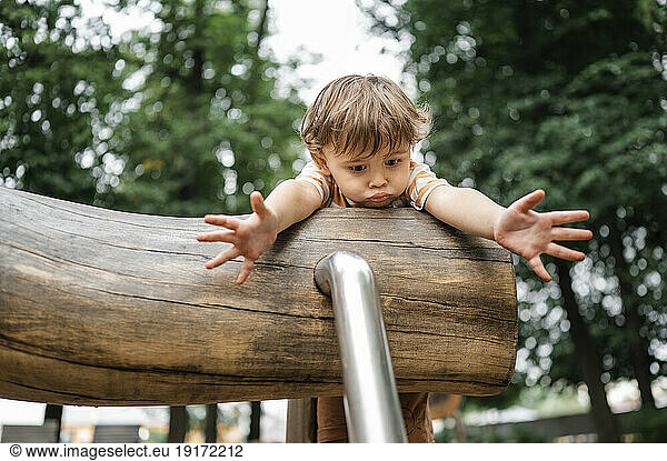 Scared boy playing on outdoor play equipment in park