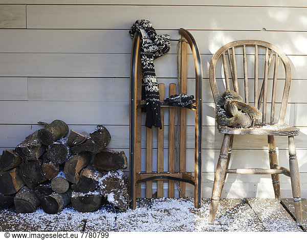 Scarf  wooden sled  chair and firewood on porch