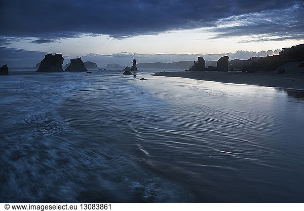 Scenic view of Bandon Beach against stormy clouds during dusk
