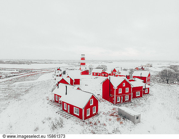 Scenic view of colorful wooden buildings top view. Fishing village and tourist town. Wooden red houses of fishing village in snowy covered in winter. A few red houses near the lighthouse on t