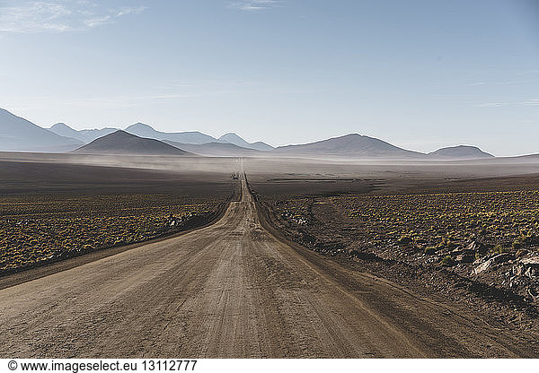 Scenic view of dirt road amidst Atacama Desert against sky