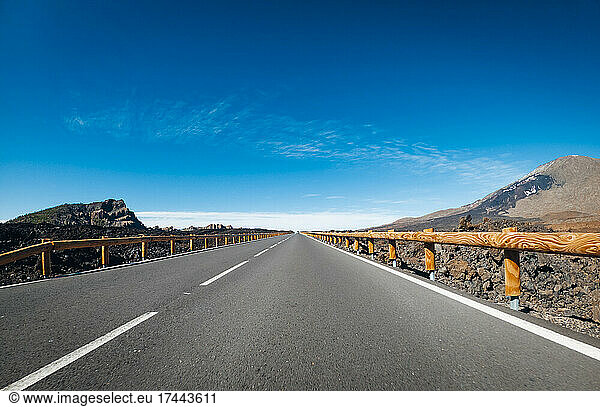 Scenic view of empty road amidst mountains on sunny day