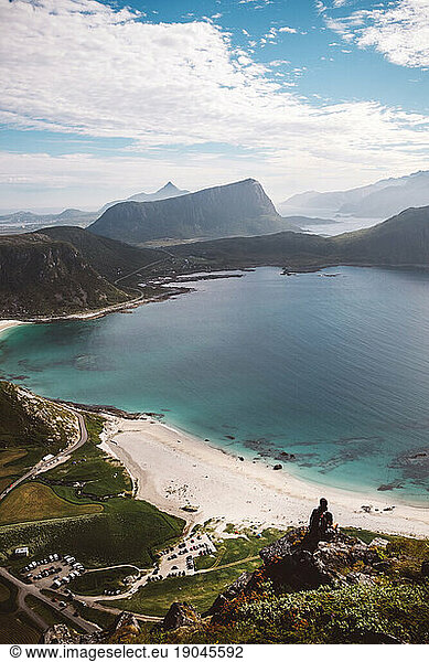 Scenic view of Haukland Beach with a man sitting on a rock
