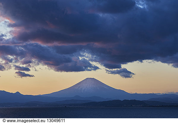 Scenic view of Honshu island by Mount Fuji against cloudy sky during sunset