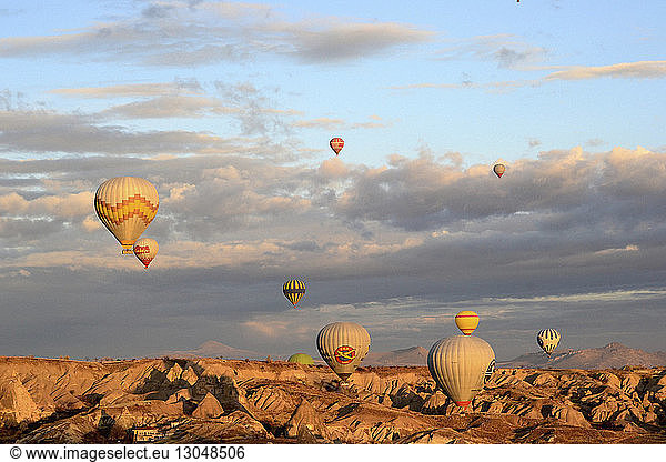 Scenic view of hot air balloons flying against cloudy sky during sunset