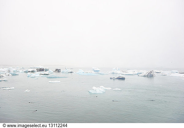 Scenic view of icebergs floating on sea against clear sky