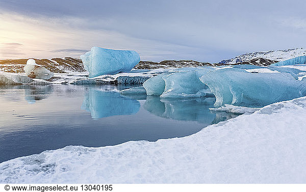 Scenic view of icebergs in lake against sky during winter