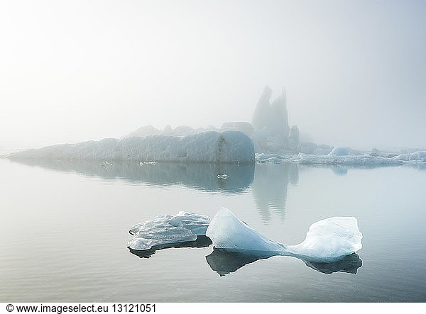 Scenic view of icebergs in sea during foggy weather