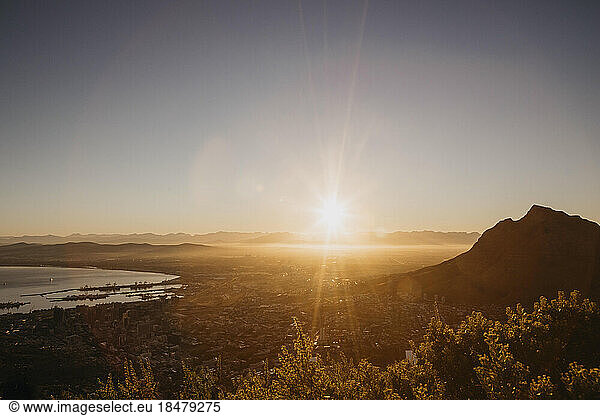 Scenic view of mountain and sea in front of clear sky at sunrise