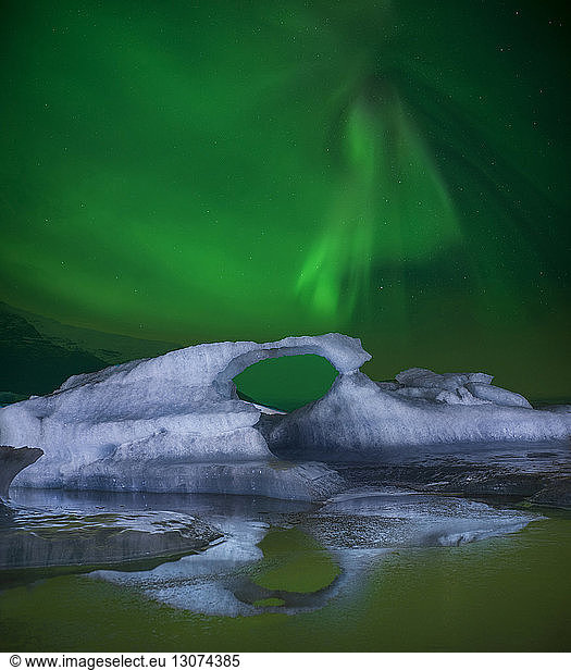 Scenic view of northern lights over icebergs in sea