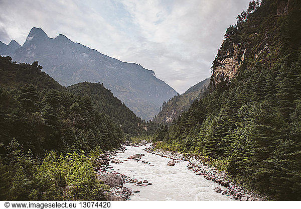 Scenic view of river flowing amidst mountains against cloudy sky at Sagarmatha National Park