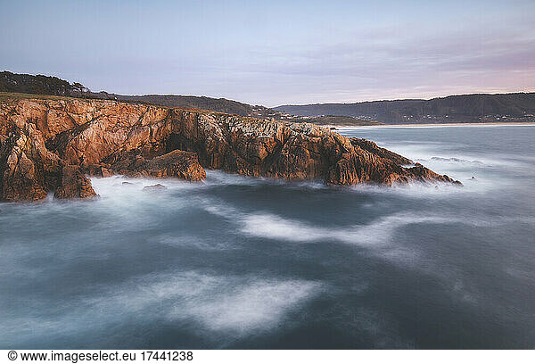 Scenic view of rocky coastline during sunset