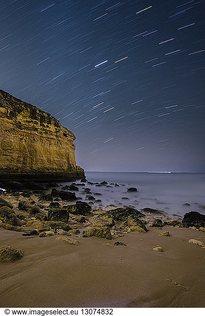 Scenic view of sea against star trails at night
